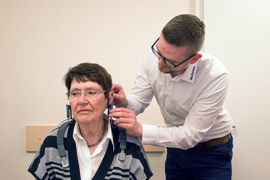 Hörtest bei älterer Frau durch Hörakustiker im Fachgeschäft für Hörgeräteberatung.